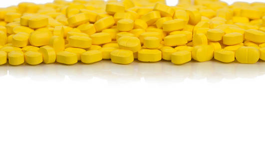 在白色背景上与复制空间隔离的黄色卵球形矩形平板药片。止痛药。制药行业。全球医疗保健理念