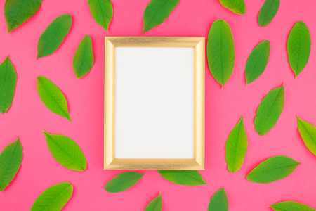 创意平躺在明亮的粉红色背景上的新鲜绿叶与金色框架模拟和复制空间在最小的流行艺术风格, 文本模板的顶部视图模式