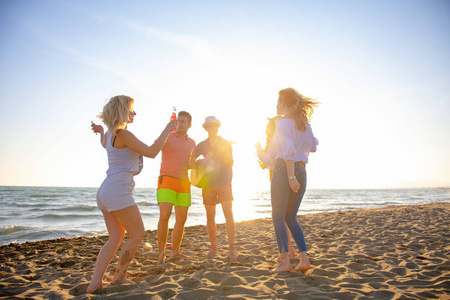 群上的美丽的夏天日落景色在海滩上跳舞的快乐年轻人