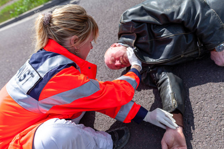 一位德国医护人员检查受伤的骑车人的血压。Rettungsdienst 是德国的救护车服务词