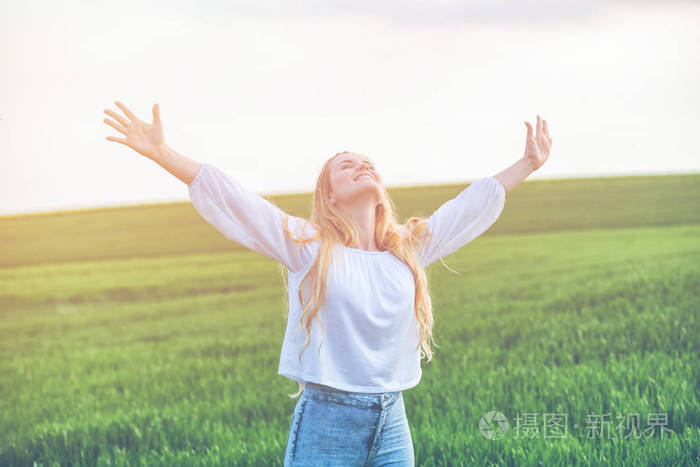 幸福微笑的女人在绿色的田野在夏天天自由概念