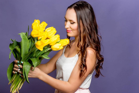 年轻漂亮的女人抱着一束黄色郁金香。春天