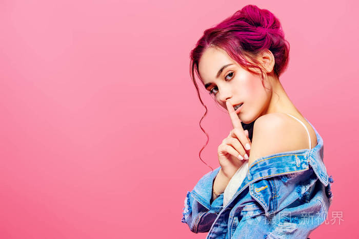 漂亮的粉红色头发的女孩穿着牛仔夹克摆在粉红色的背景.