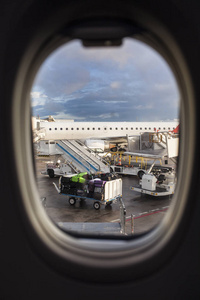从飞机的窗口内看到的机场跑道, 手提箱和移动梯