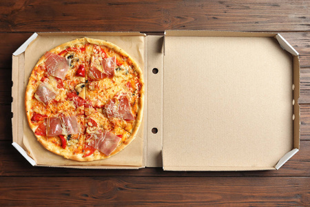 纸箱与美味的比萨饼在木质背景, 顶部视图