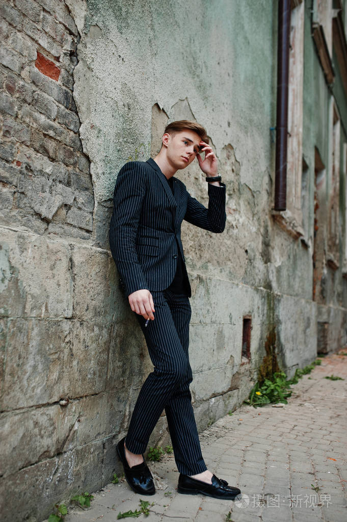 年轻男子气概的男孩穿上拉丁时尚夹克吸烟在街上