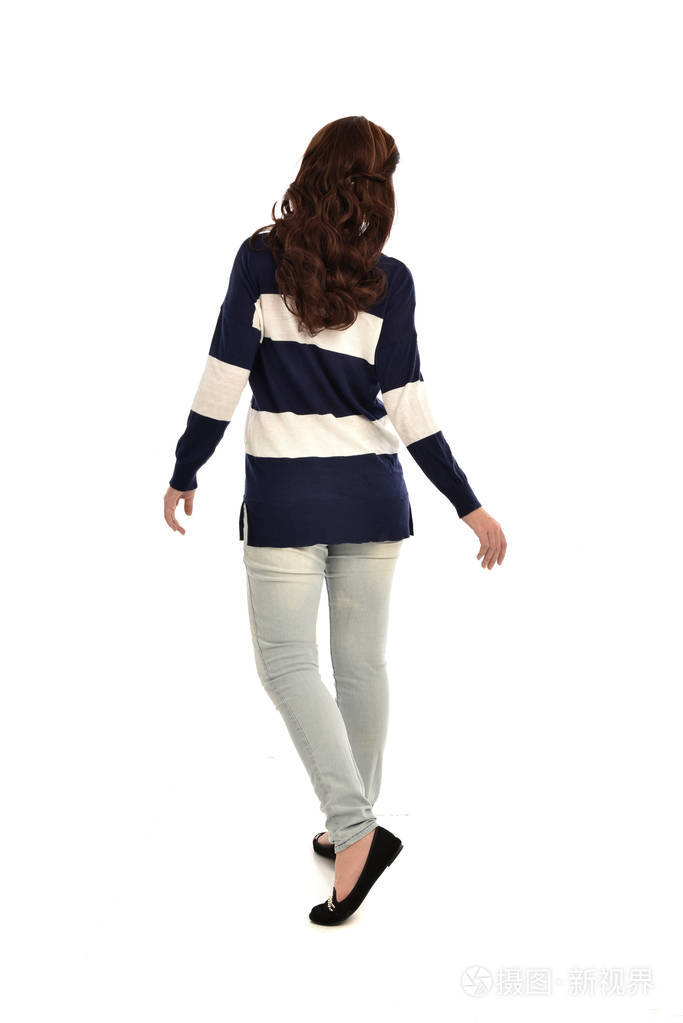 穿牛仔裤和休闲跳线的女孩的全长肖像.站立的姿态, 被隔绝在白色演播