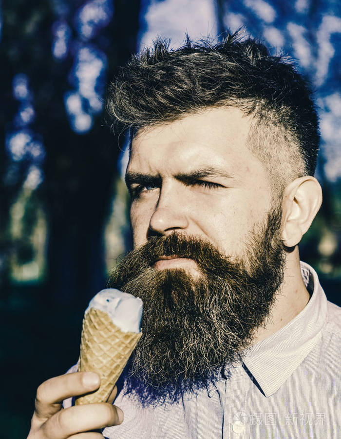 一个长胡子的男人在阳光明媚的炎热的日子里用冰淇淋锥凉着, 关上了.