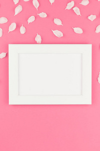 创意平躺概念白色框架模型的顶部图和苹果树花花瓣在柔和的粉红色背景与拷贝空间在极小的样式, 文本模板