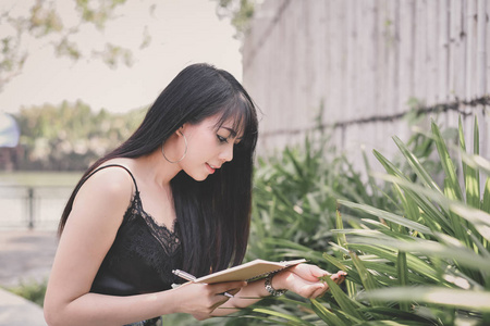 教育理念。亚洲妇女在公园看书。美丽的女人在公园里放松。美丽的女人是快乐的阅读