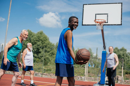 跨种族的老年运动员在操场上一起打篮球