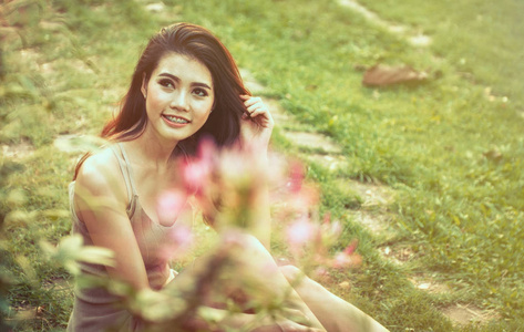 亚洲漂亮的女孩坐在公园在绿色草地上