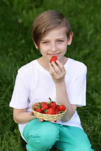 绿色草篮中有机草莓的可爱男孩