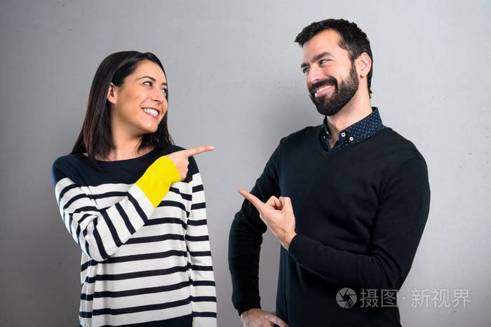 一对夫妇在灰色背景上互相指指点点