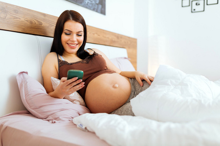 美丽的孕妇使用手机
