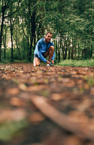 适合男性慢跑者系鞋带一天训练的跨国家森林小道赛跑时自然公园