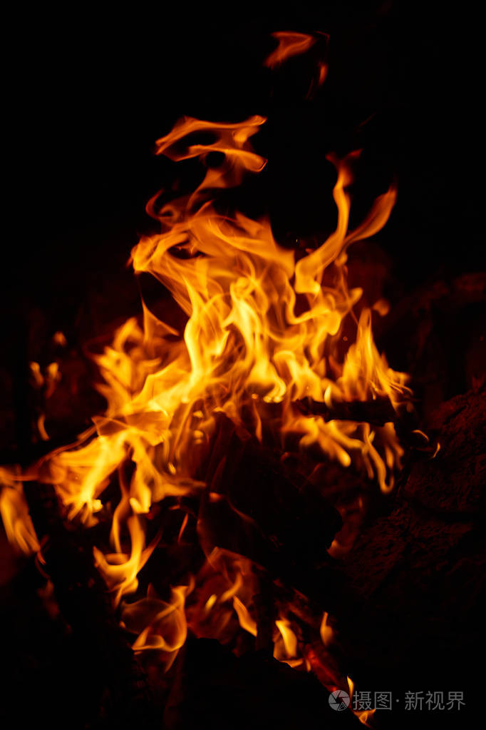 在黑暗的背景下燃烧木柴的美丽燃烧的火焰
