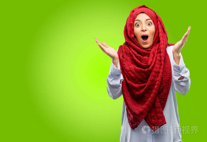年轻的阿拉伯妇女戴着头巾高兴和惊喜欢呼表达哇手势
