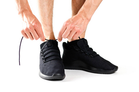 一个男人把鞋带系在黑色运动鞋上。运动。在白色背景上被隔离