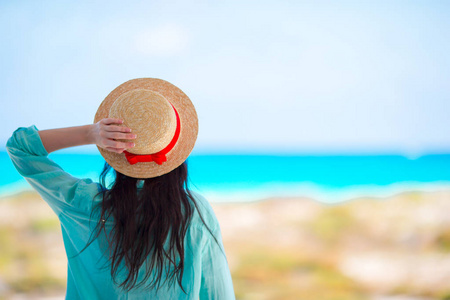 年轻女子在热带的海滩上的帽子