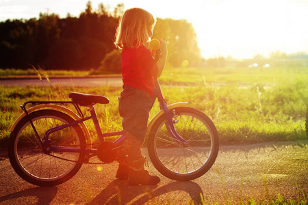 在日落时的小女孩骑自行车
