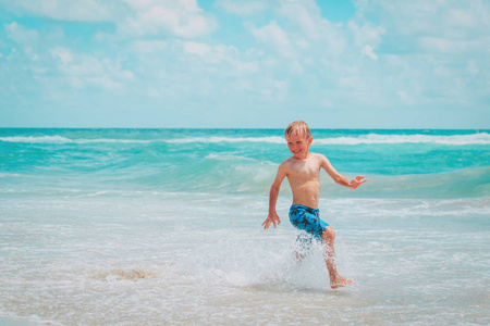 快乐的小男孩奔跑玩与水享受海滩