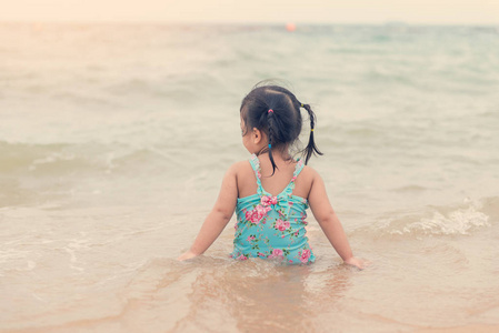 小女孩坐在沙滩上玩沙子