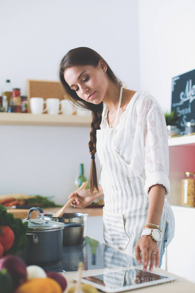 厨房里用木勺做饭的女人.烹调妇女