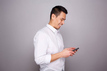 微笑中年男子肖像在灰色背景下的手机上阅读短信