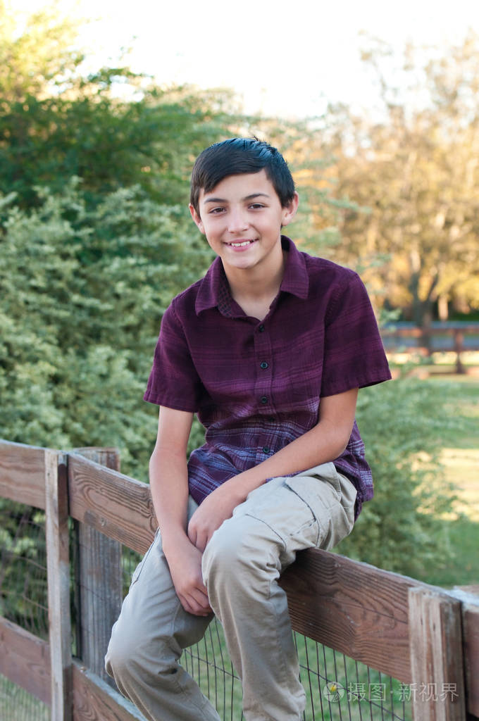 可爱的小男孩,坐室外的篱笆上的侧面肖像