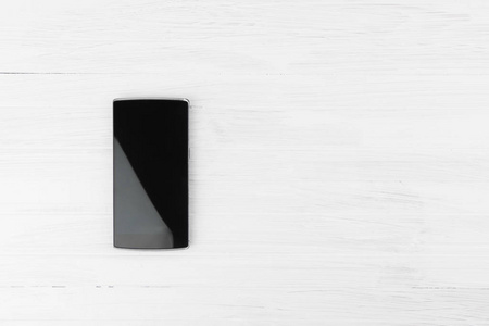 黑色智能手机在白色的木材背景与空白空间的文本上角