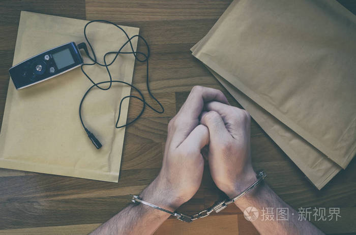 被捕的人.把手铐放在警察局桌子上的男人的手上