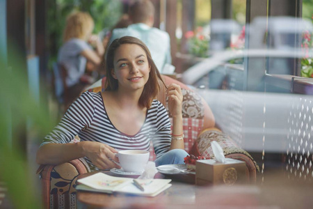年轻女子坐在室内在城市的咖啡馆
