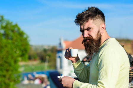 有胡子的男人用咖啡杯喝咖啡男人用胡子和胡子严脸喝咖啡, 城市背景, 弥散。咖啡打破概念。长胡子的人看起来严厉和严肃