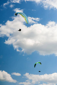 两个滑翔在蓝天下飞翔, 乌云密布。阳光明媚的一天, 天空中的滑翔伞