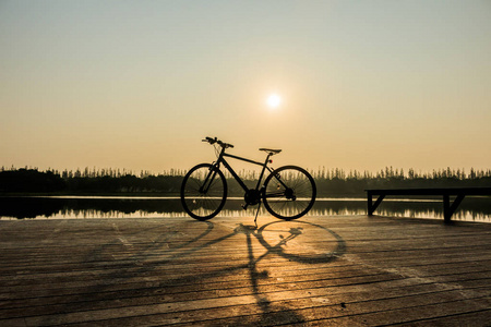 自行车靠近湖和日落在美丽的天空的轮廓