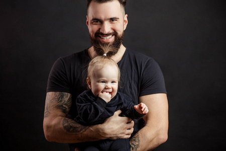 年轻的运动父亲与可爱的婴儿在黑色背景