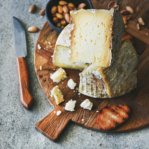 乳酪拼盘与乳酪分类, 坚果, 蜂蜜和面包在乡下木板在灰色具体背景