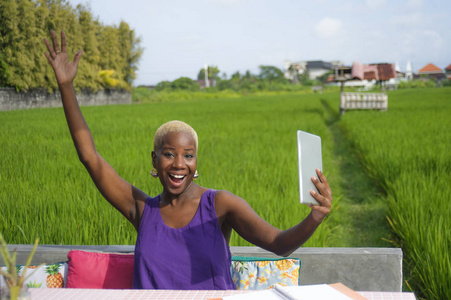 年轻的迷人和快乐的成功黑人非洲裔美国妇女与数字平板电脑垫户外在绿色领域咖啡馆微笑欢快的数字游牧成功和在线自由职业者的工作