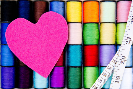 缝纫线线轴与粉红毛毡的心和卷尺