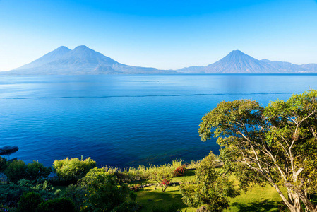 从湖阿特蒂兰湖的看法在清晨, 蓝色天蓝和清澈的水, 美丽的魔法湖与火山和土著居民在危地马拉高地图片采取接近巴哈契最旅游城市那里