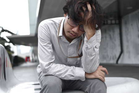 厌倦无聊的亚洲商人坐着感到沮丧照片