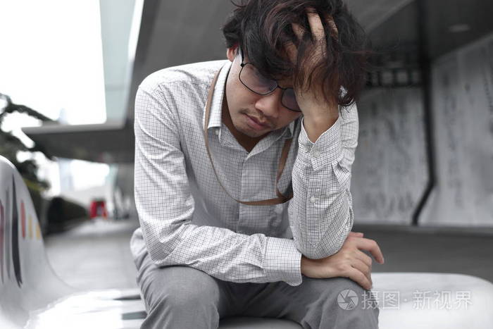厌倦无聊的亚洲商人坐着感到沮丧