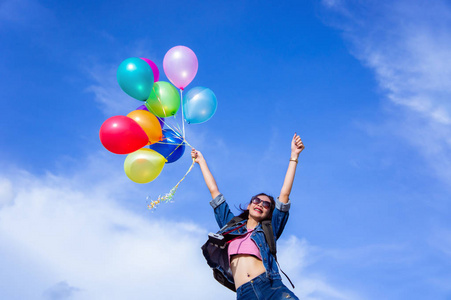 跳跃的女孩在明亮的天空背景举行一个光颜色球