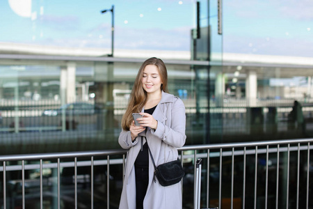 在手提箱和机场附近用智能手机聊天和浏览的年轻女性人