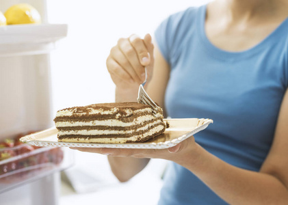 从冰箱中摄取美味的高卡路里甜点的女人, 节食失败和不健康的食物概念