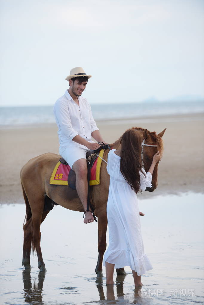 浪漫夫妇与骑马在海滩上的下午在一个甜蜜的假期