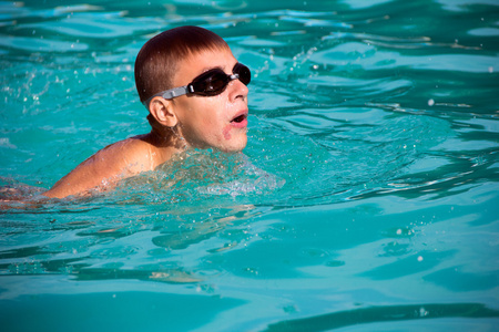 男孩在游泳池游泳照片