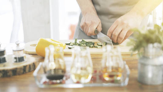 男性炊具手切片黄瓜在木制的烹饪板上