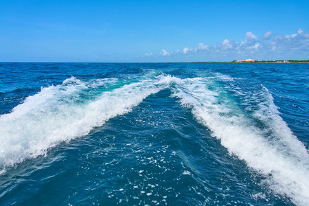 在加勒比海坎昆墨西哥的快速移动马达双体船后水面的踪迹。夏日晴朗的日子, 蓝天白云